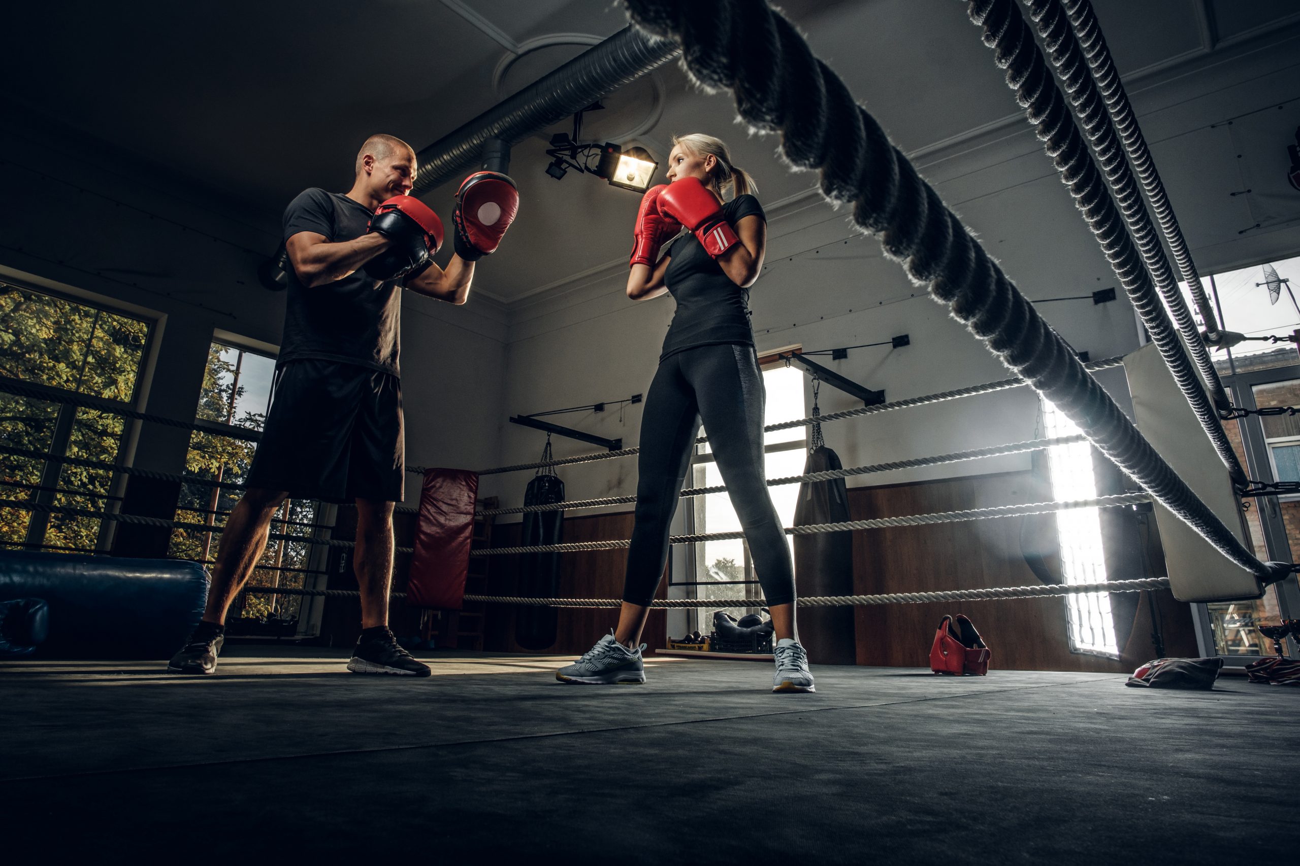 Boxing trainer and his new student have a sparring on the ring wearing boxing gloves.